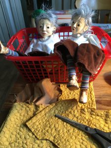 Two puppets lying in a basket waiting for their clothing to be finished